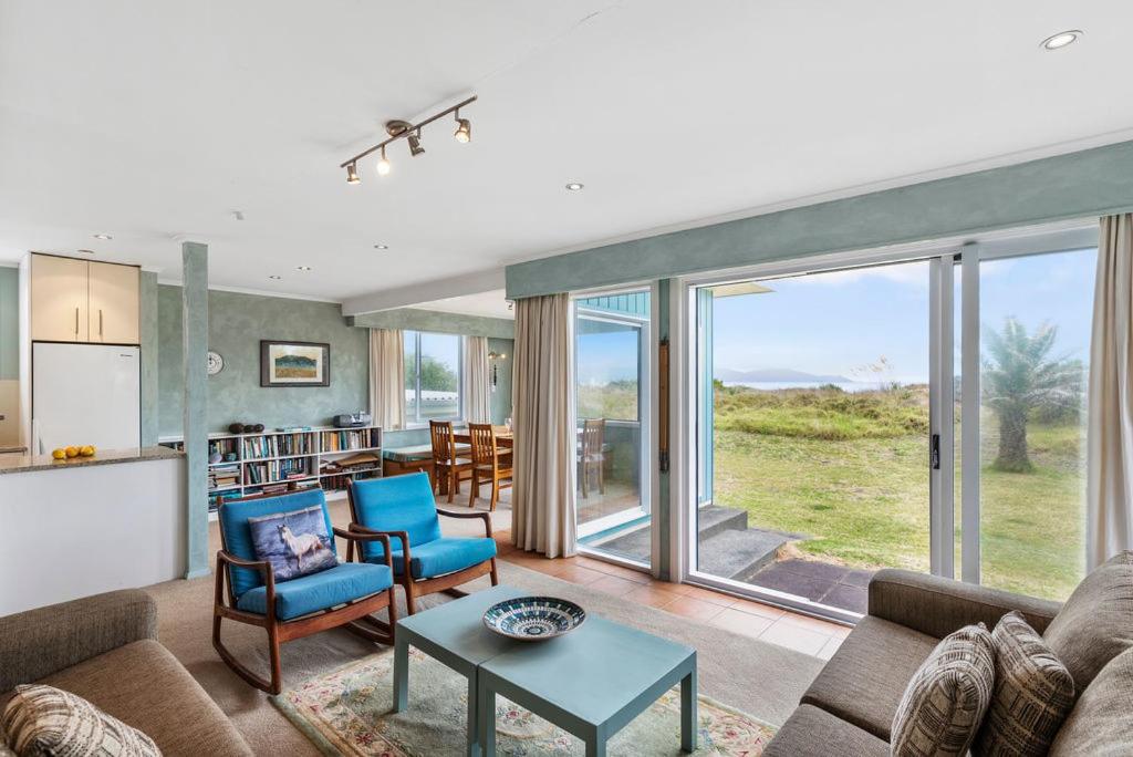 ein Wohnzimmer mit einem Sofa und einem Tisch in der Unterkunft La Casa de la Playa - Beachfront Waikanae Home in Waikanae