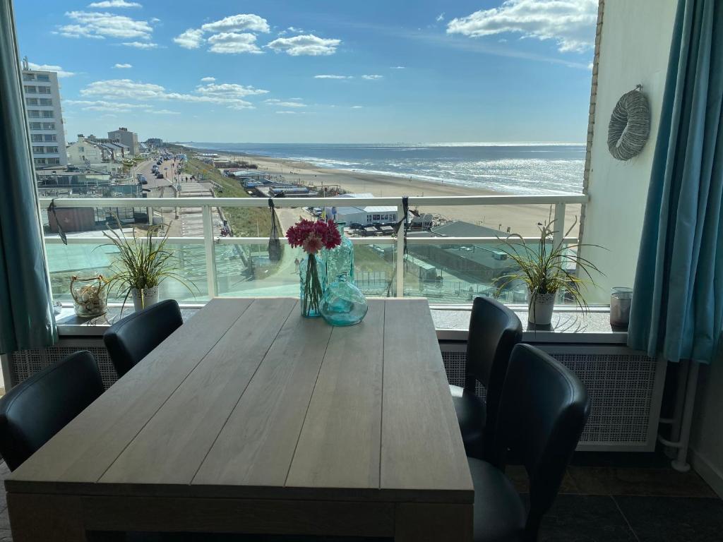 uma mesa de madeira com cadeiras e um vaso com flores em Berrie's Sea View em Zandvoort