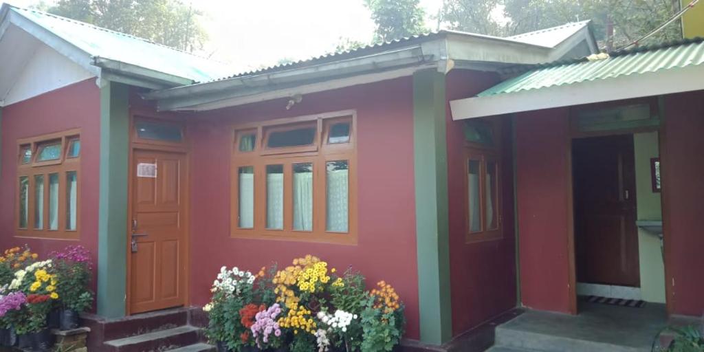 a red house with flowers in front of it at Vamoose Shri Ganesh Homestay in Māngwa