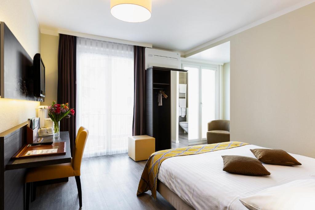 a bedroom with a bed and a table with a desk at Hôtel Bellerive in Lausanne