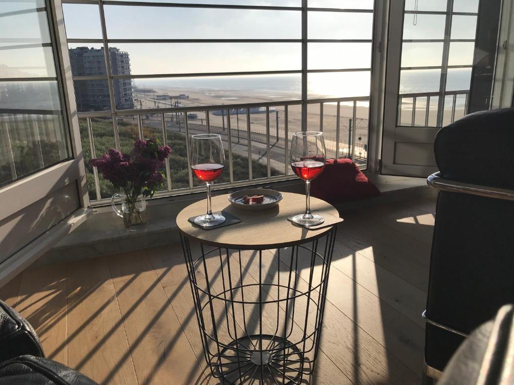 dwa kieliszki wina siedzące na stole na balkonie w obiekcie Into the Sea w mieście Middelkerke