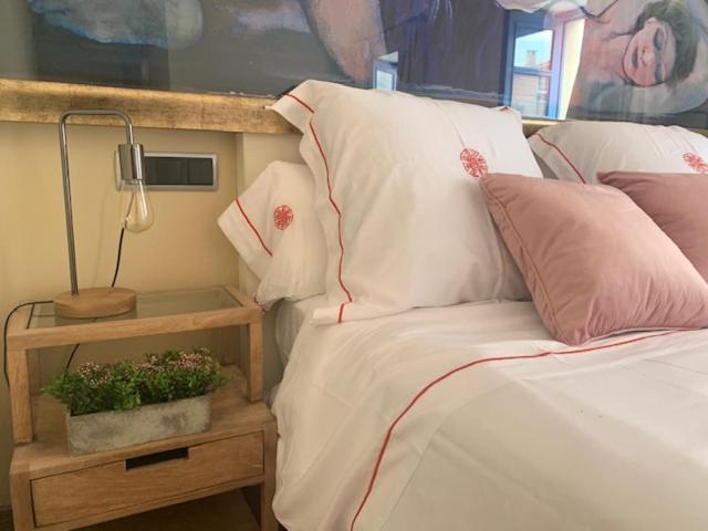1 cama con sábanas blancas, almohadas rosas y lámpara en CASA DO ARXENTINO, en Mera