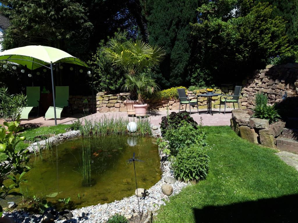 - un jardin avec un étang et une table avec un parasol dans l'établissement Ferienwohnung Trommblick - Natur Pur - Rimbach im Odenwald, à Rimbach