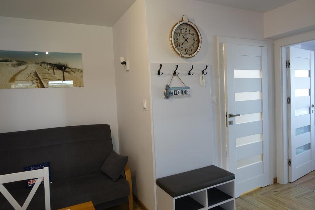 a living room with a couch and a clock on the wall at APARTAMENT PRZY PLAŻY in Rowy