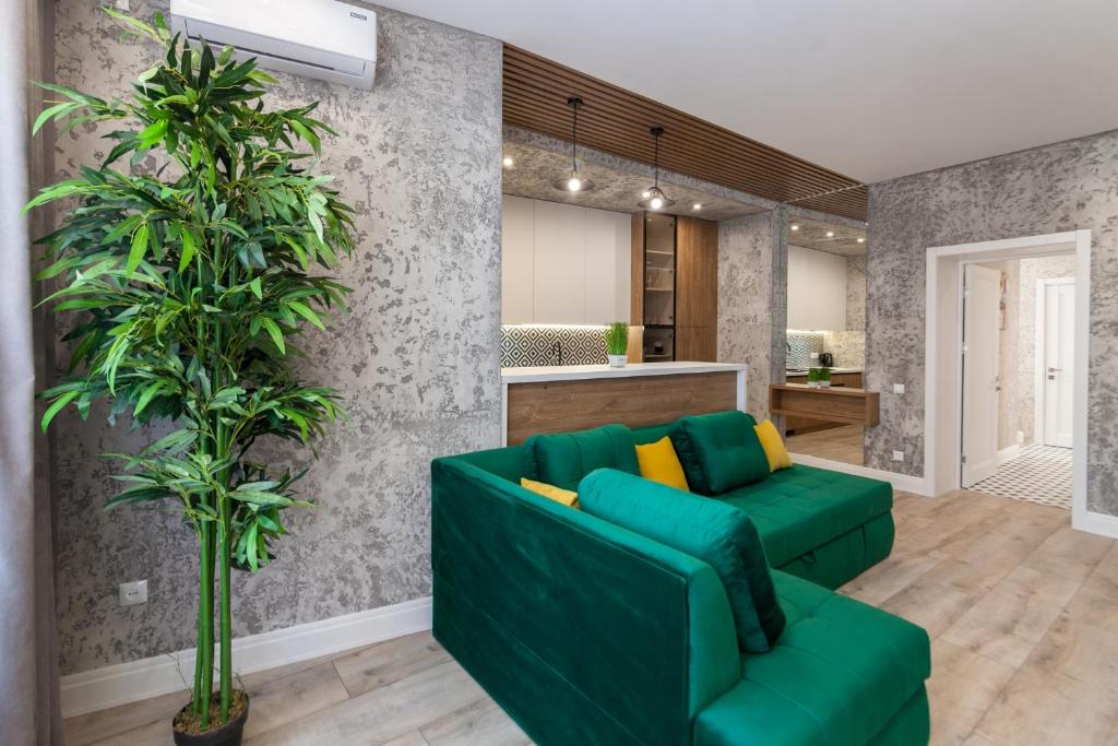 un salon avec un canapé vert et une plante dans l'établissement Royal VIP Apartment on Pidmurna 24, à Lviv