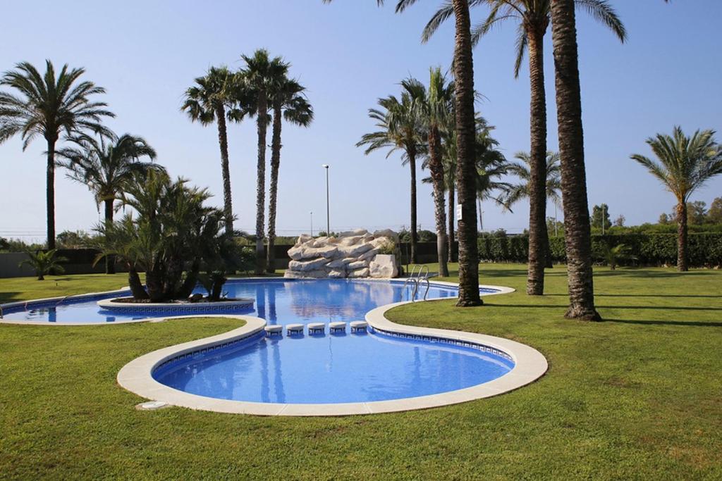 una piscina con palmeras en un parque en AT119 Nova Torredembarra, en Torredembarra