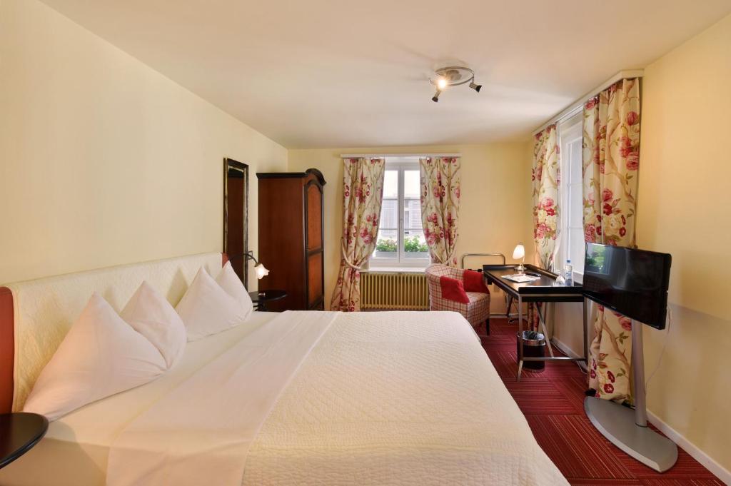 a bedroom with a large white bed and a desk at Romantik Hotel Schwan in Horgen