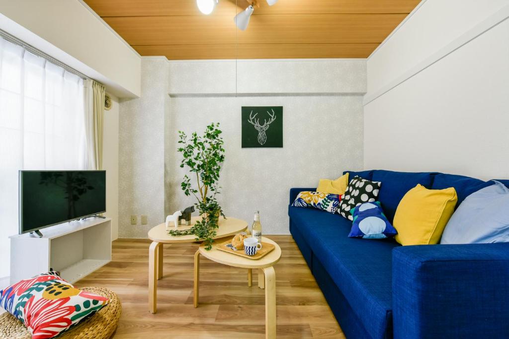 uma sala de estar com um sofá azul e uma mesa em 札幌市中心部大通公園まで徒歩十分観光移動に便利なロケーションh207 em Sapporo