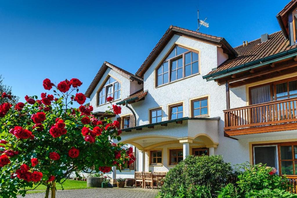ein großes Haus mit roten Blumen davor in der Unterkunft Appartementhaus Achmannhof in Bad Füssing