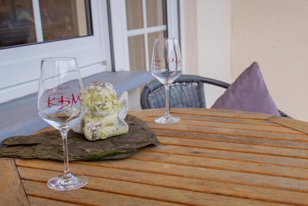 two wine glasses sitting on a wooden table at Ferienwohnung Weingut KDM in Kröv