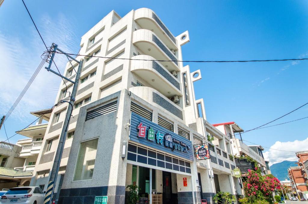 a tall white building with a sign on it at 花蓮自由行民宿 in Hualien City