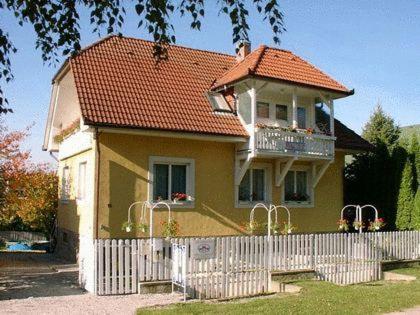 a yellow house with a white fence in front of it at Apartman Hévíz Holiday in Hévíz
