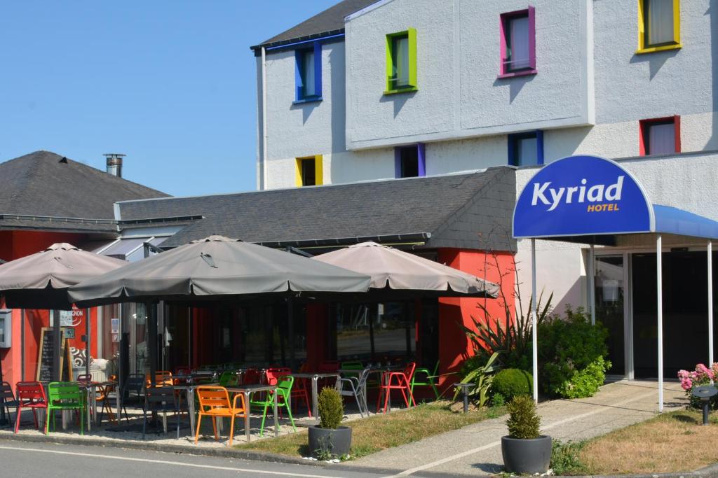 a restaurant with tables and umbrellas in front of a building at Kyriad Rennes Sud - Chantepie in Chantepie