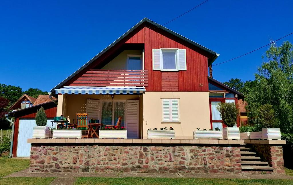une maison rouge et blanche avec un mur en pierre dans l'établissement Villa Felícia, à Balatonszepezd