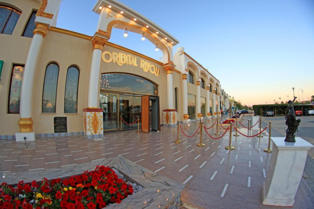 een groot gebouw met rode bloemen ervoor bij Oriental Rivoli Hotel & Spa in Sharm El Sheikh