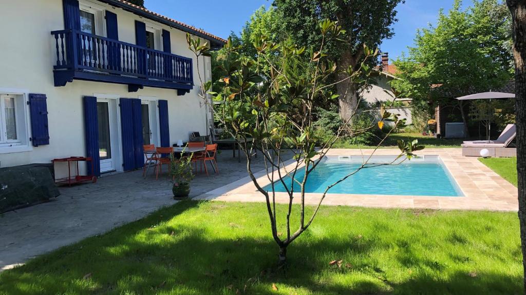 a small tree in front of a house with a swimming pool at Les Chênes in Bénesse-Maremne