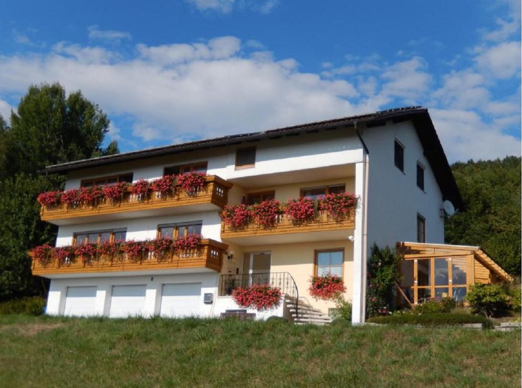 ein weißes Gebäude mit Blumen auf den Balkonen in der Unterkunft Ferienwohnung Hirtreiter in Lalling