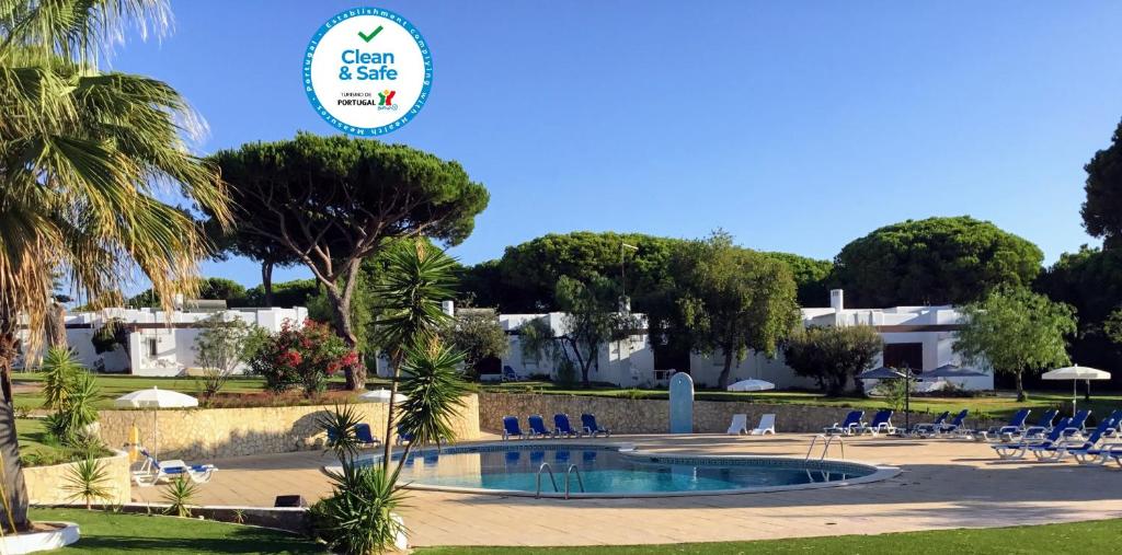 um resort com uma piscina com cadeiras e árvores em Prado Villas em Vilamoura