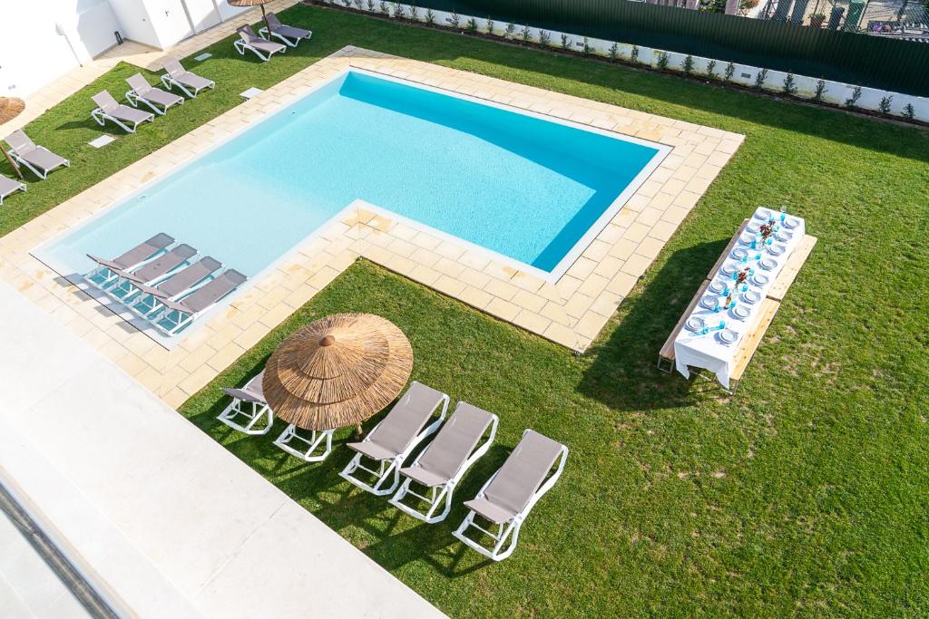 een uitzicht over een zwembad met stoelen en een parasol bij Villa Mena in Barriga