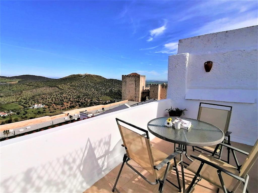 a glass table and chairs on a balcony with a view at Casa da Beata in Elvas