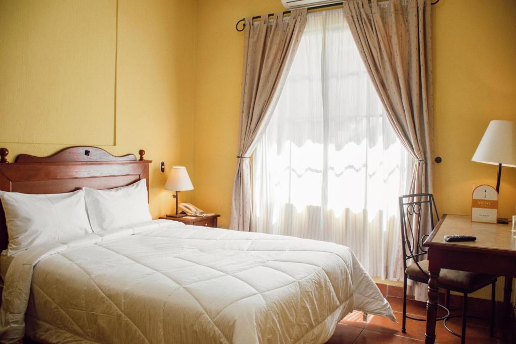 a bedroom with a bed and a window and a desk at Hotel Villa Terra in San Salvador