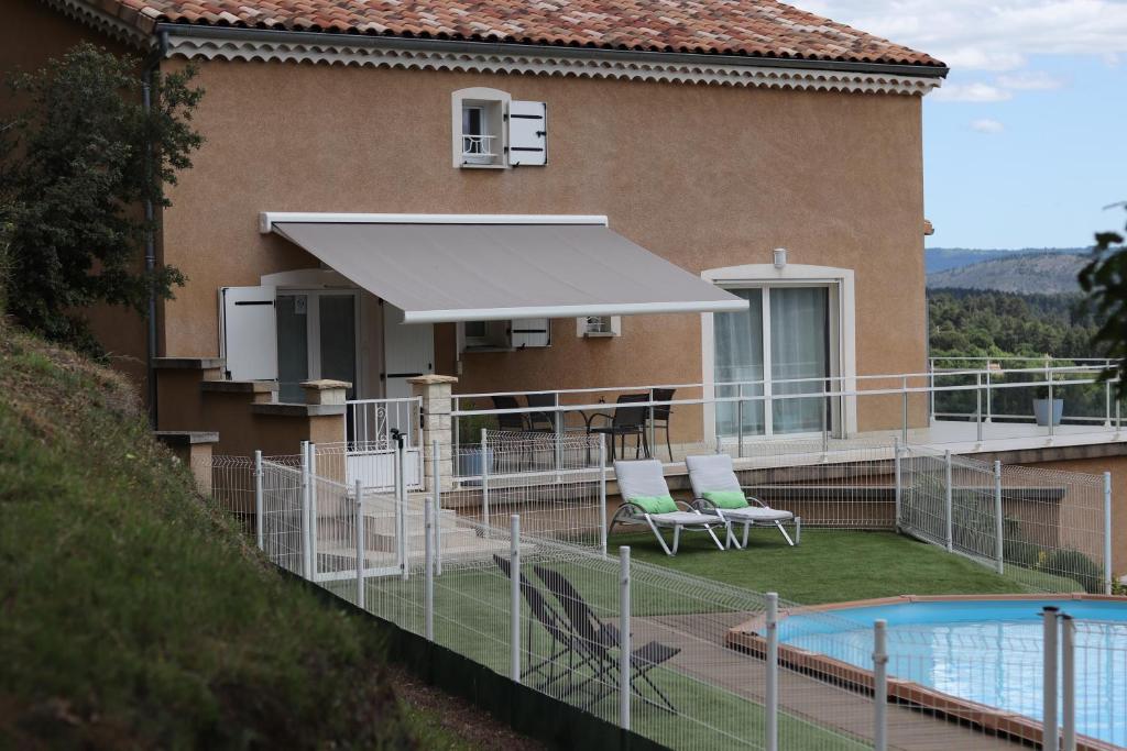 a house with a swimming pool and a white umbrella at Les Clos De La Vigne in Vals-les-Bains