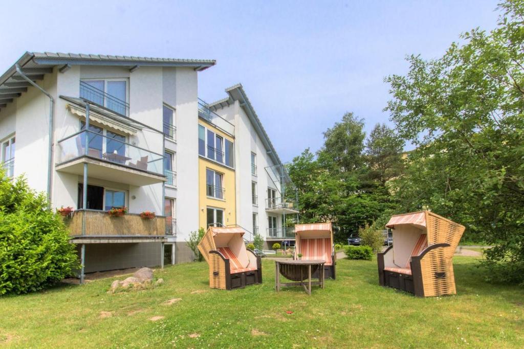 un patio con sillas y una mesa frente a un edificio en Strandmuschel en Ostseebad Sellin