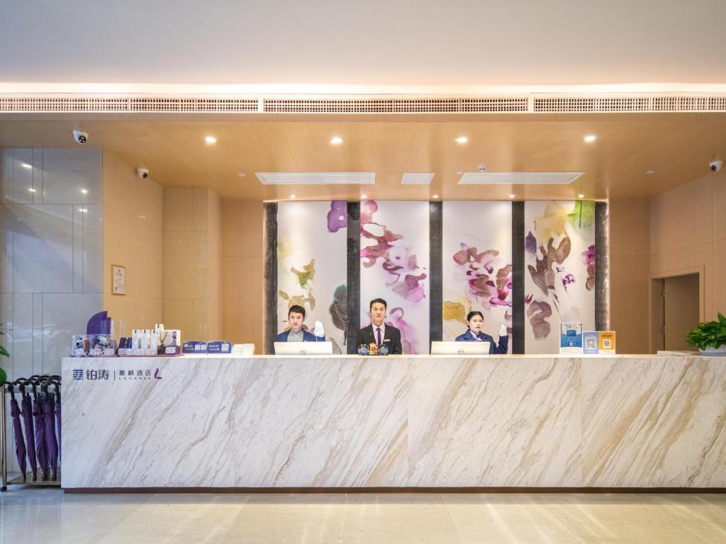 a group of people sitting at a counter in a lobby at Lavande Hotel Qingzhen Vocational Education City Time Guizhou in Guiyang
