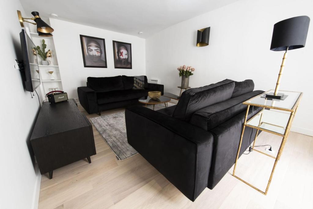 ein Wohnzimmer mit einem schwarzen Sofa und einem Tisch in der Unterkunft Voyageur sans bagage in Paris