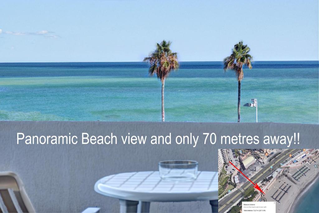 uma vista para a praia com uma mesa e palmeiras em Beachfront Parque Paloma em Benalmádena