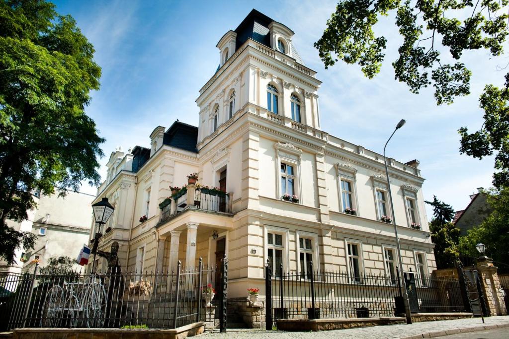 un edificio blanco con una torre encima en Hotel Ambasada Bolesławiec, en Bolesławiec