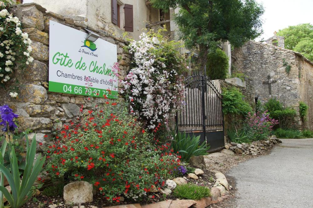 ein Schild an der Seite eines Gebäudes mit Blumen in der Unterkunft Chambres d´Hôtes Prieuré d'Orniols in Goudargues