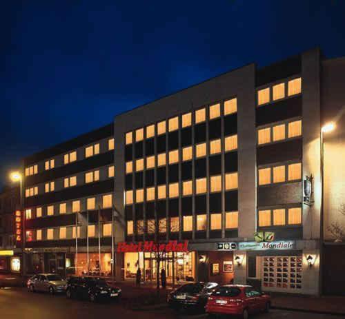 un gran edificio con coches estacionados frente a él en Hotel Mondial, en Langenfeld