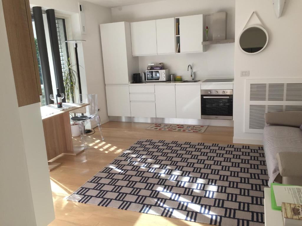 una cocina con armarios blancos y una alfombra blanca y negra en Appartamento Ligeia en Bolzano