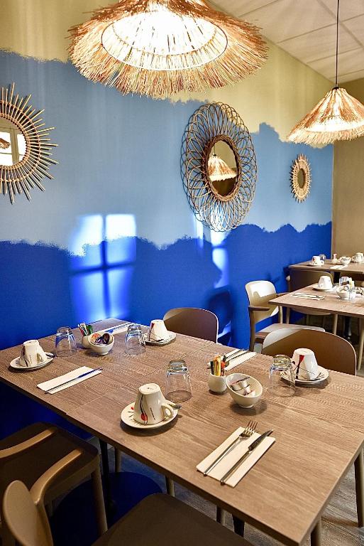 une salle à manger avec une table et un mur bleu dans l'établissement Hotel Majestic, à Nîmes