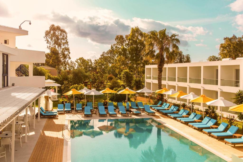 une image d'une piscine de l'hôtel avec des chaises et des parasols dans l'établissement Nasos Hotel & Resort, à Moraitika