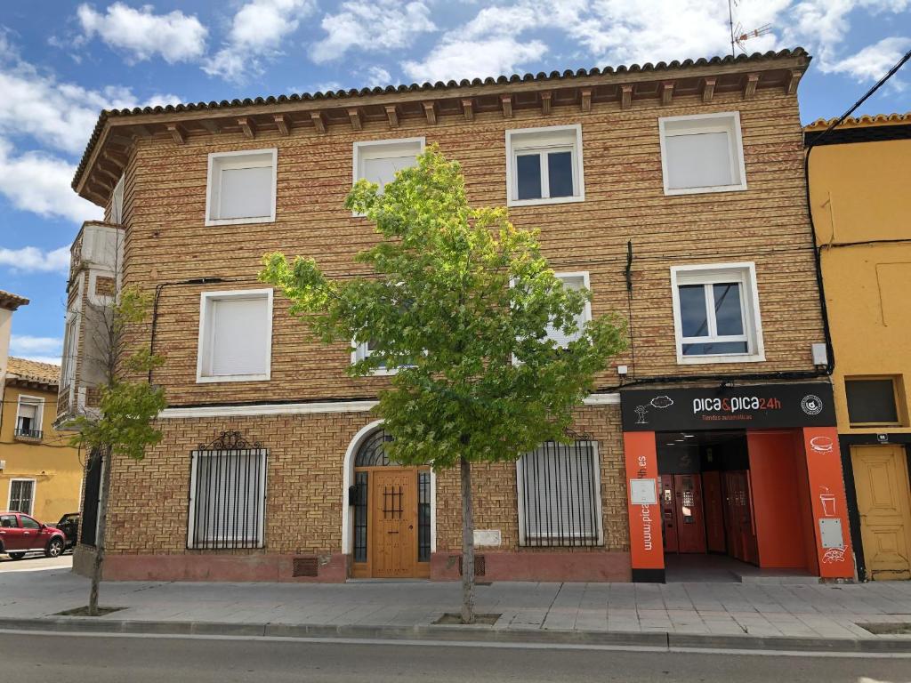 un bâtiment en briques avec un arbre devant lui dans l'établissement La Maison del Gállego, à Villanueva de Gállego