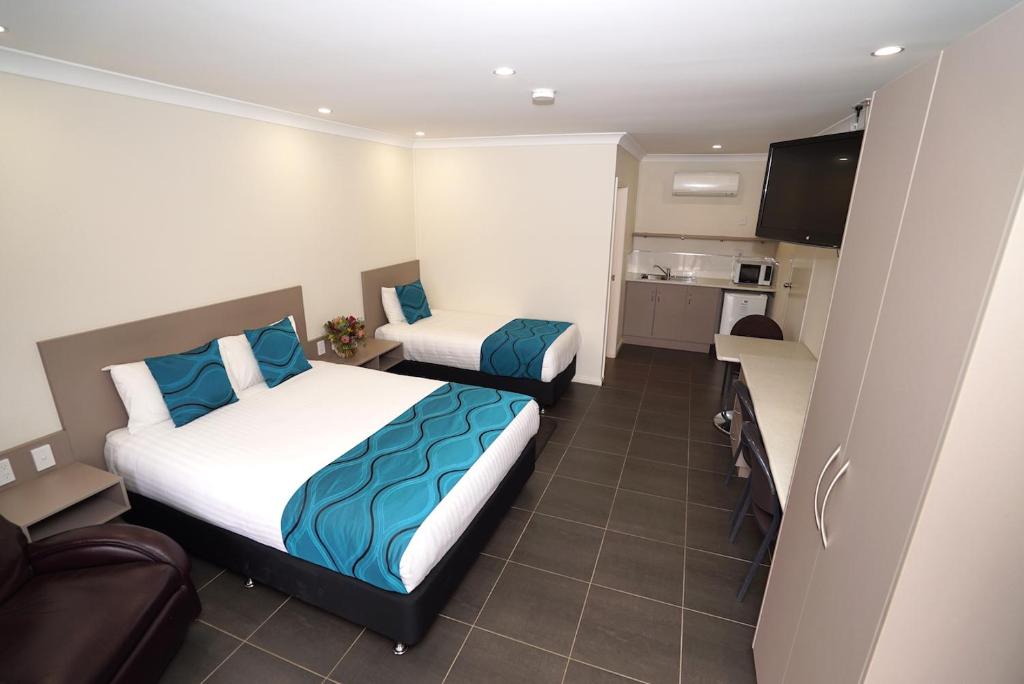 a small bedroom with two beds and a kitchen at Exies Bagtown in Griffith