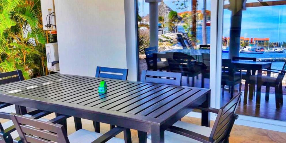 a green candle sitting on a wooden table on a patio at Tommy Coconut's waterfront apartment Sailaway with private beach in Jan Thiel