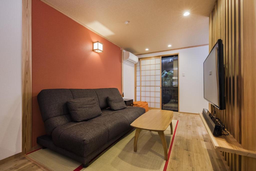 a living room with a couch and a tv at Shiki Homes ZEN FUYACHO in Kyoto