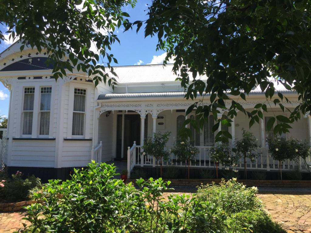 a white house with a white fence in front of it at Chelsea House Bed & Breakfast in Whangarei