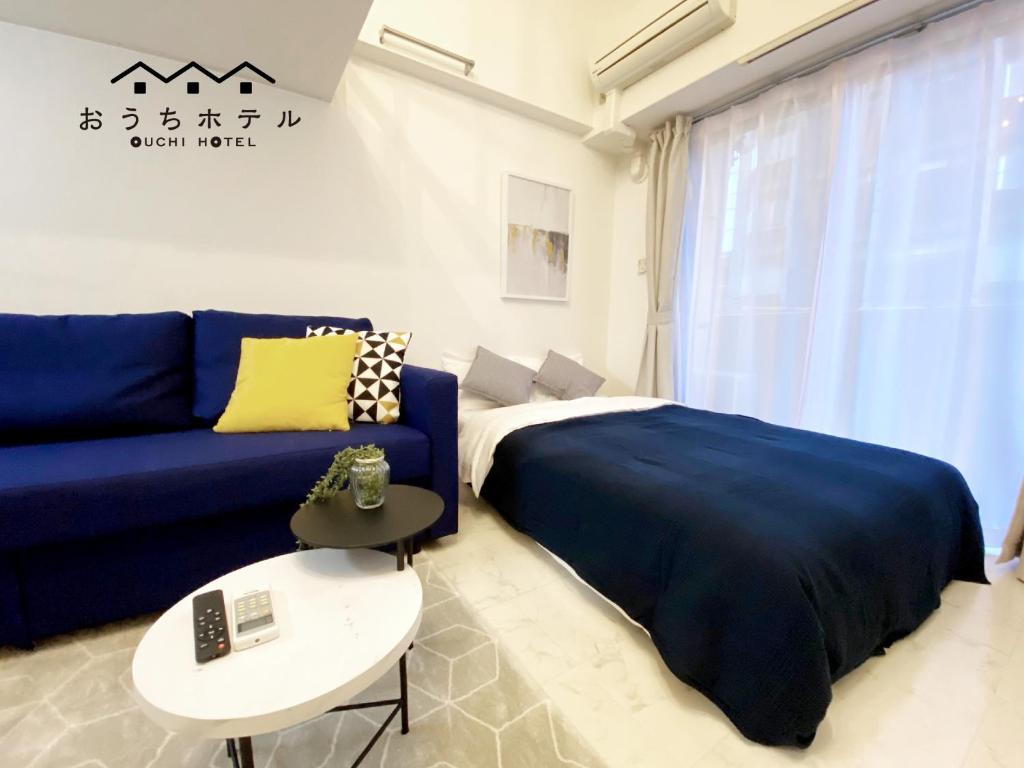 ein Schlafzimmer mit einem blauen Sofa und einem Tisch in der Unterkunft OUCHI HOTEL Higashi-Hiratsuka #201 in Hiroshima