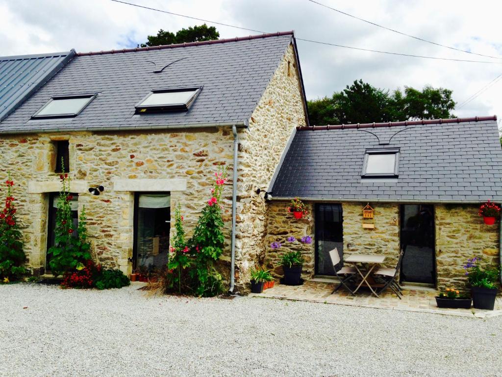 a stone house with flowers in front of it at L'Etable in Digosville