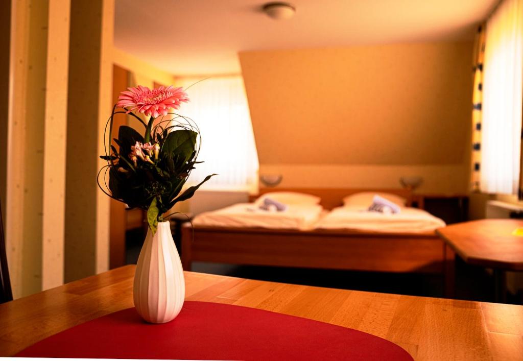 a white vase with flowers on a table in a room at Havergoh Wander- & Fahrrad-Hotel in Horn-Bad Meinberg