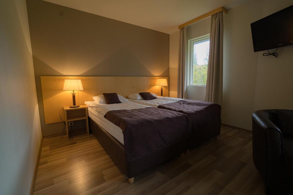 a bedroom with a bed with two lamps and a window at Hotel Hallormsstadur in Hallormsstaður