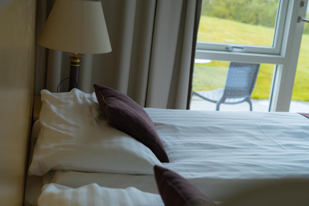 a bedroom with a bed with pillows and a window at Hotel Hallormsstadur in Hallormsstaður