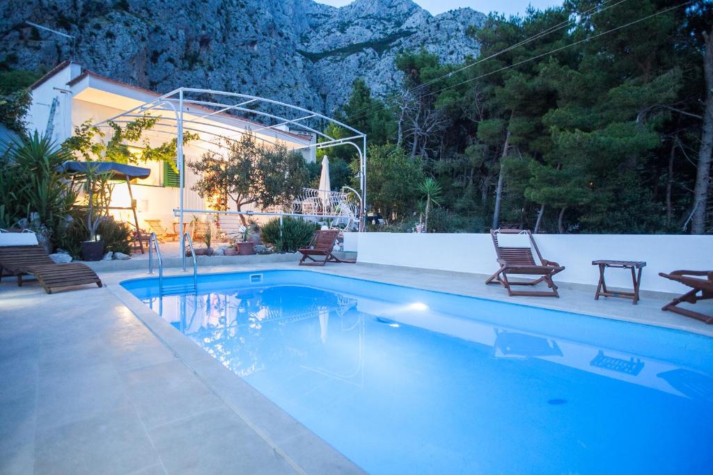 a swimming pool with two chairs next to a house at Villa Ana in Makarska