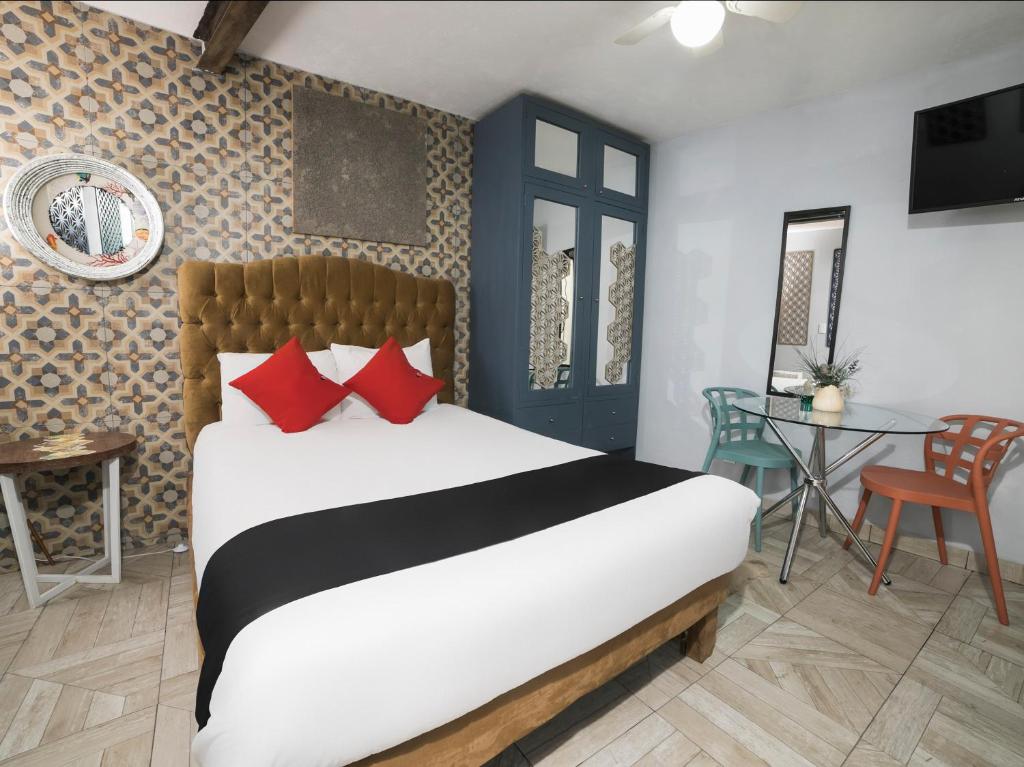 Un dormitorio con una cama con almohadas rojas y una mesa. en Coyotito Beds Coyoacan, suites a tu alcance!!!, en Ciudad de México