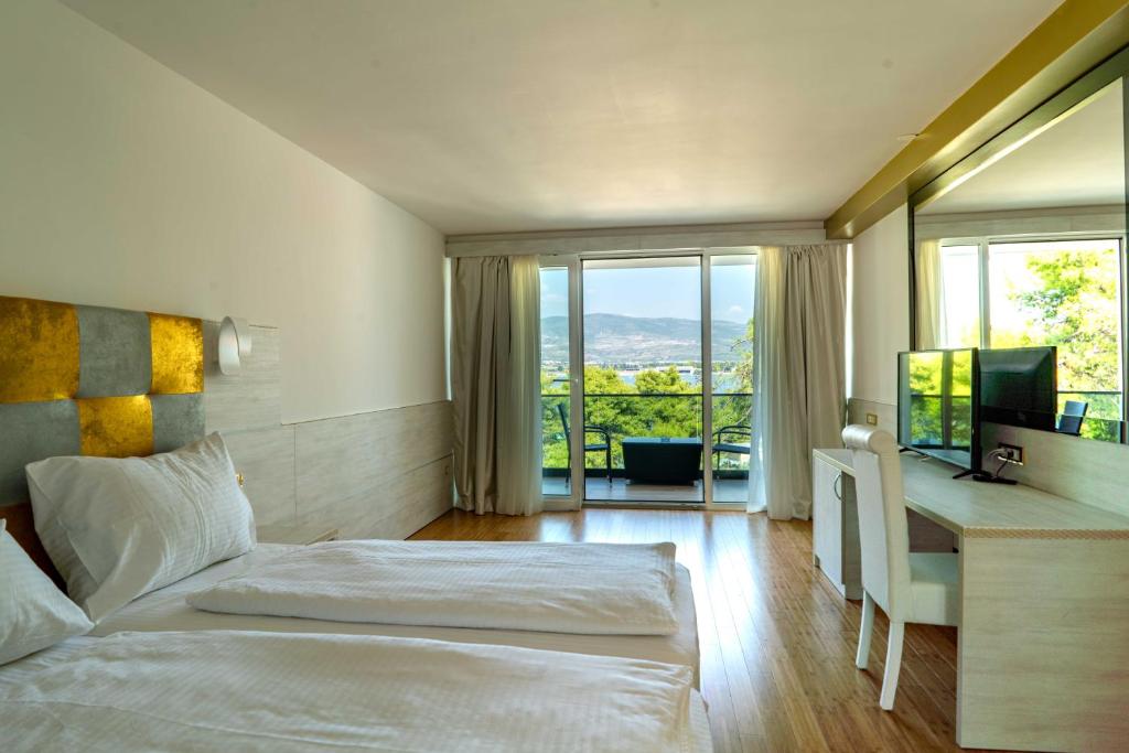 a bedroom with a bed and a desk with a television at Hotel Sveti Kriz in Trogir