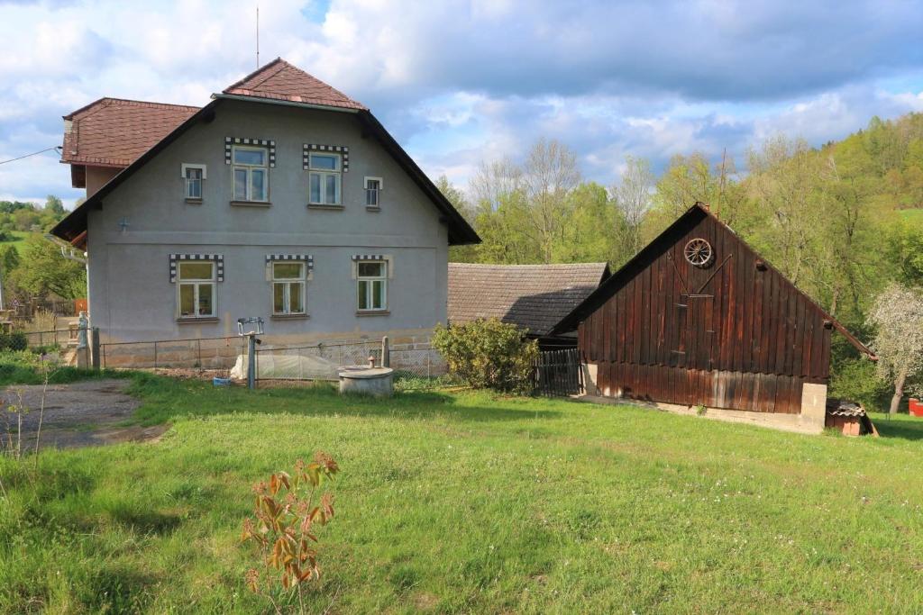 ein großes Haus und eine Scheune auf einem Feld in der Unterkunft Ubytování Na Sýpce in Bělá